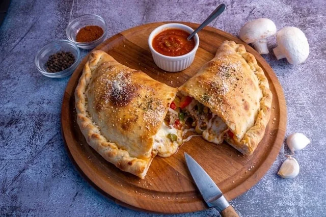 Golden calzone cut open on a wooden serving board