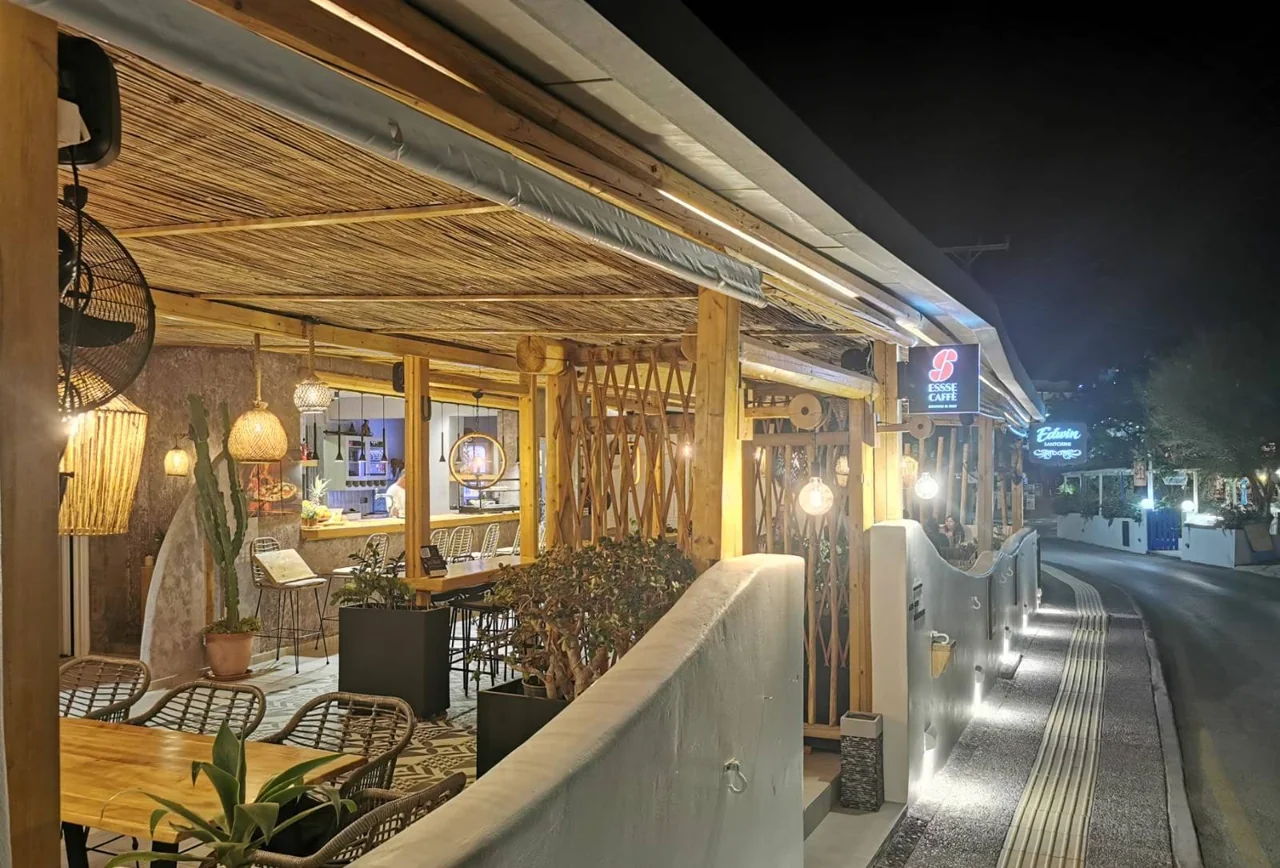The current Pizza Edwin terrace in Kamari, with woven lamps, natural wood and welcoming outdoor tables